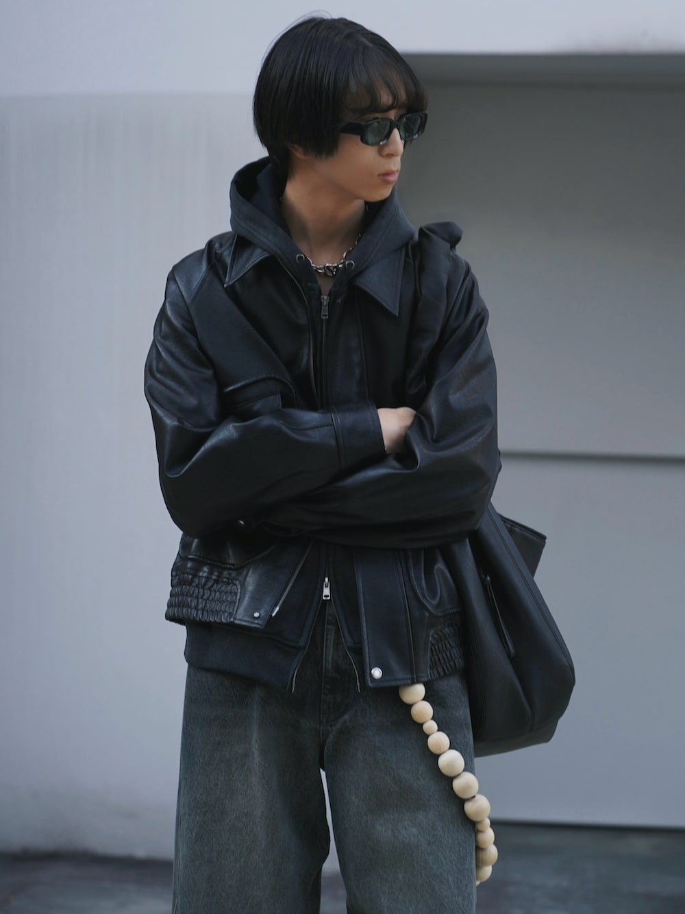 ブラック系のブルゾン、ブラック系のパーカー、ブルー系のデニムパンツを着用したメンズの冬コーディネートの3枚目の写真