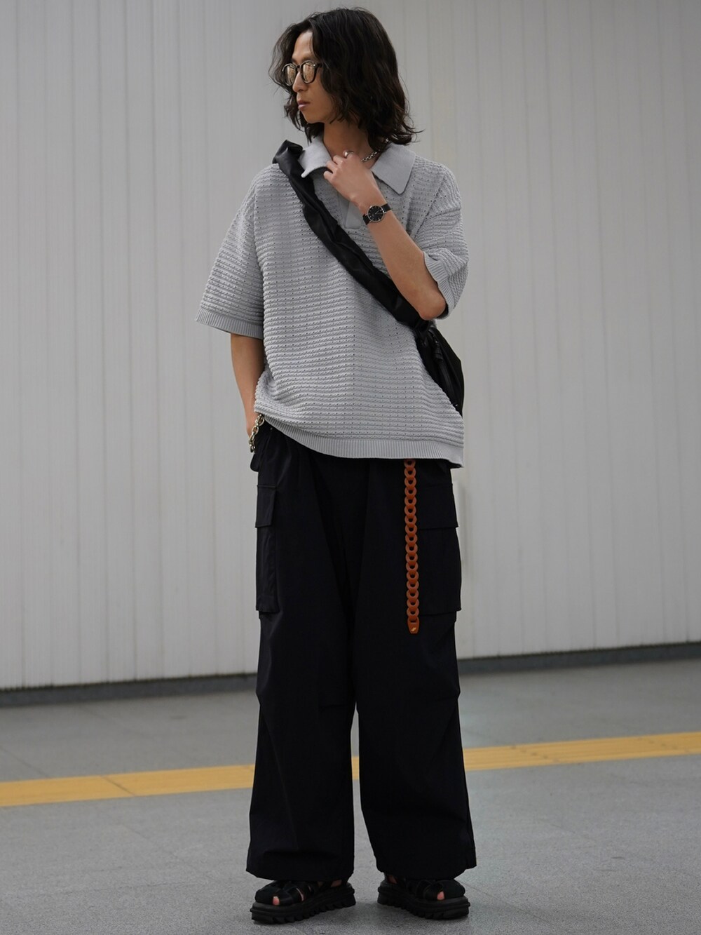 グレー系のポロシャツ、ブラック系のカーゴパンツ、ブラック系のサンダルを着用したメンズの冬コーディネートの2枚目の写真