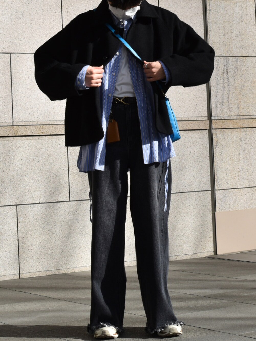 ブルー系のショルダーバッグ、ブルー系のビジネスシャツ、ブラック系のデニムパンツを着用したメンズの冬コーディネートの2枚目の写真