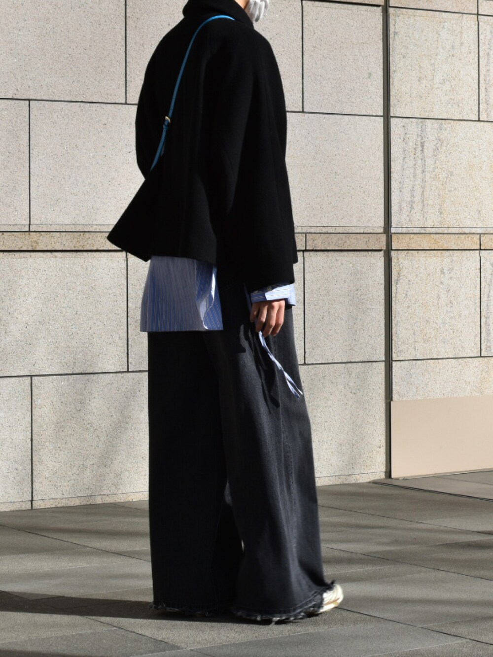 ブルー系のショルダーバッグ、ブルー系のビジネスシャツ、ブラック系のデニムパンツを着用したメンズの冬コーディネートの5枚目の写真