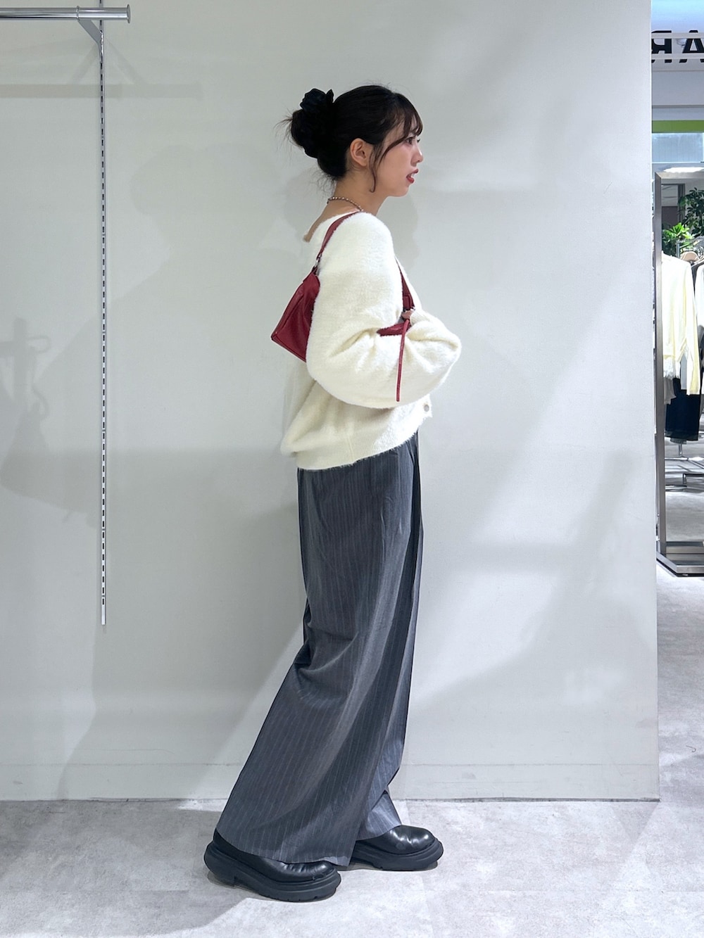 グレー系のスラックス、ホワイト系のニット/セーター、レッド系のショルダーバッグを着用したレディースの秋コーディネートの2枚目の写真