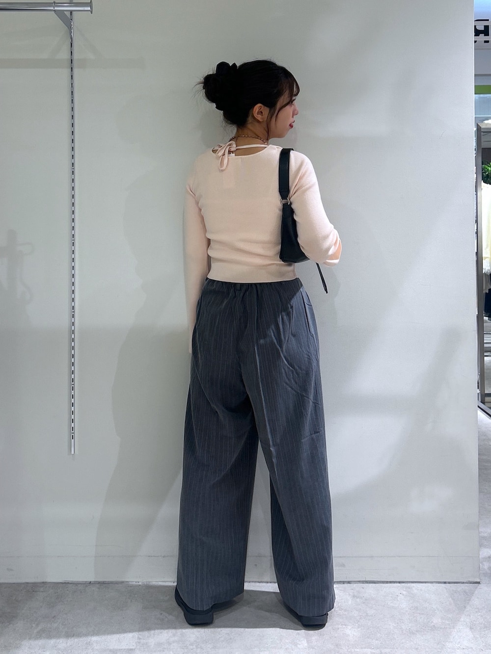ピンク系のニット/セーター、グレー系のスラックス、ブラック系のショルダーバッグを着用したレディースの秋コーディネートの3枚目の写真