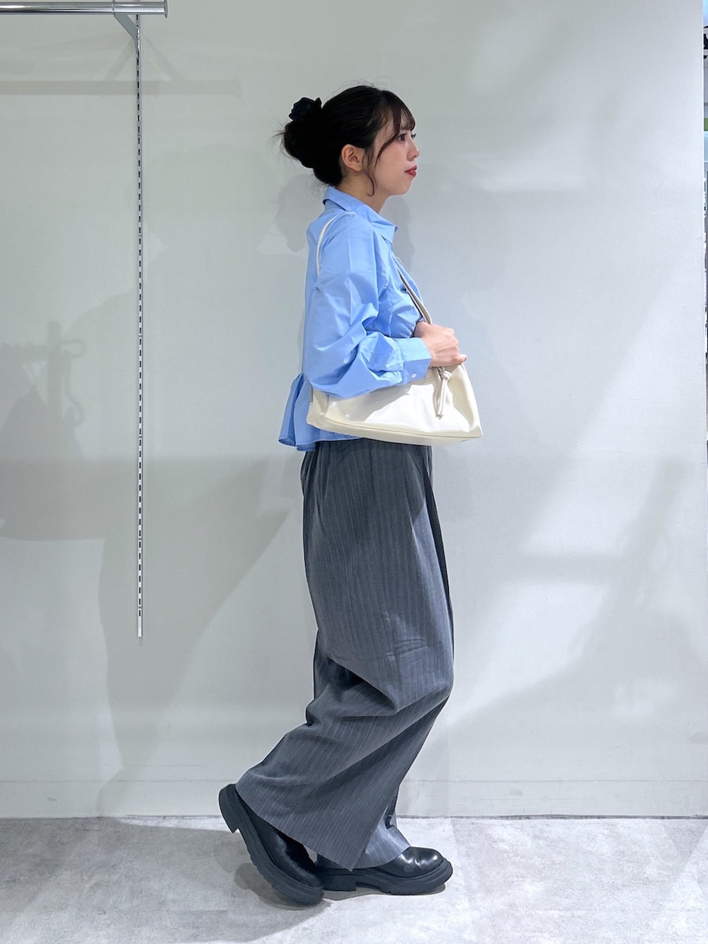 ブルー系のシャツ/ブラウス、グレー系のスラックス、ホワイト系のショルダーバッグを着用したレディースの秋コーディネートの2枚目の写真