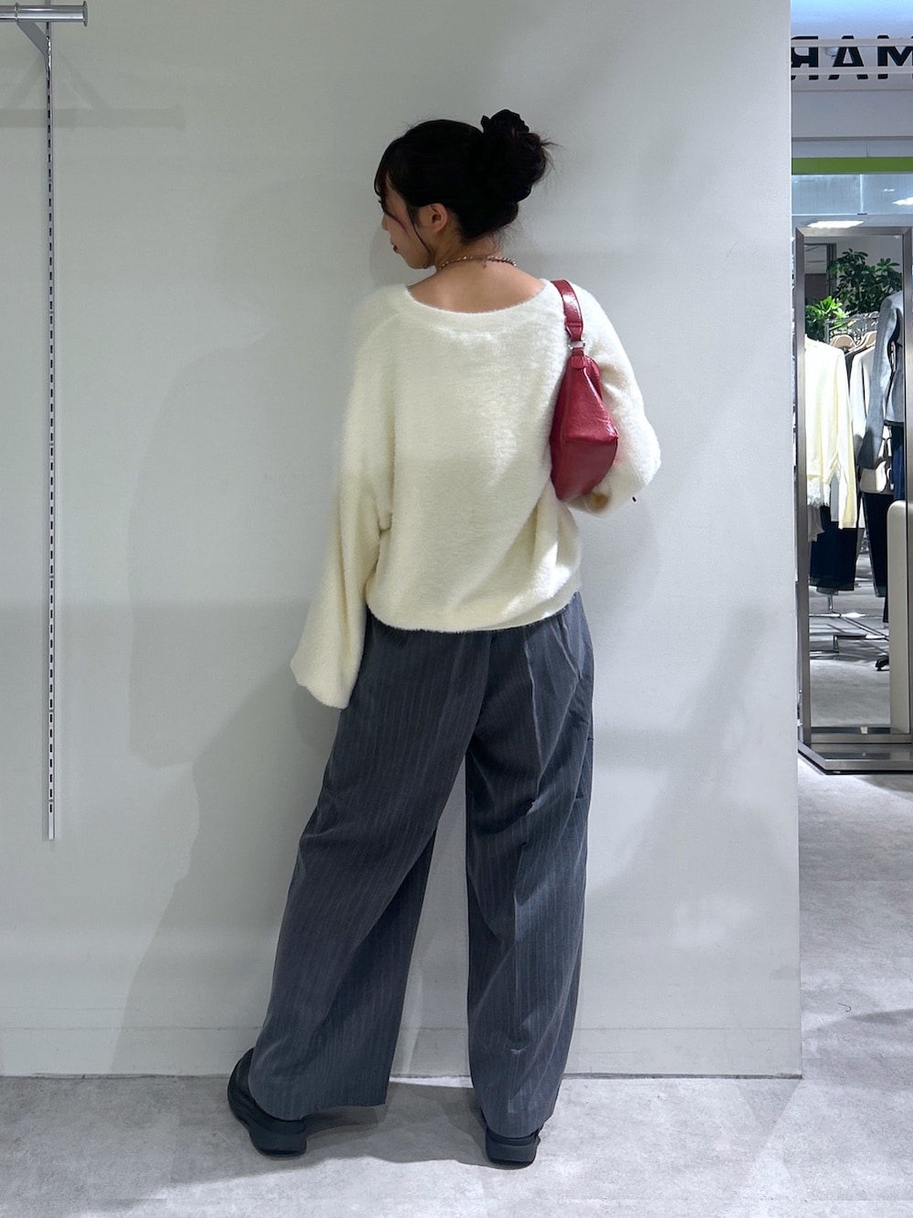 グレー系のスラックス、ホワイト系のニット/セーター、レッド系のショルダーバッグを着用したレディースの秋コーディネートの3枚目の写真