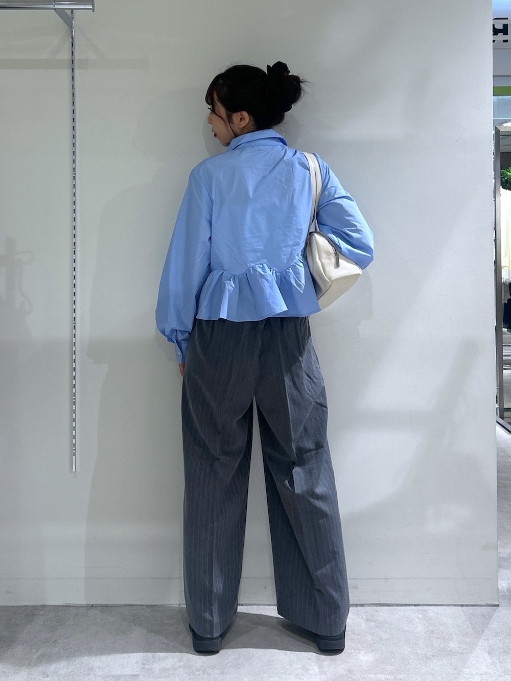 ブルー系のシャツ/ブラウス、グレー系のスラックス、ホワイト系のショルダーバッグを着用したレディースの秋コーディネートの3枚目の写真