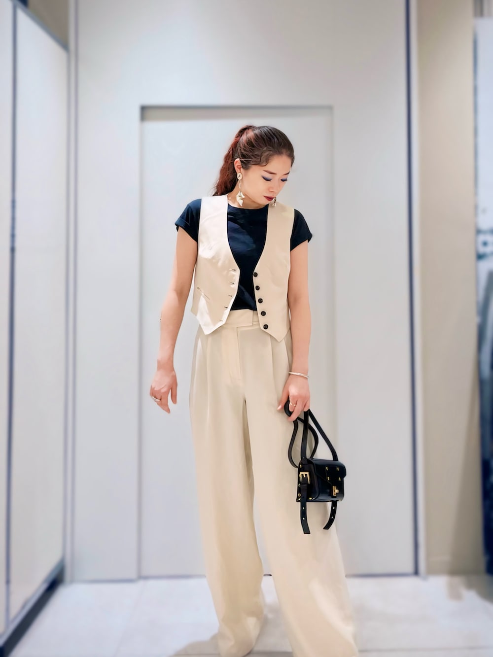 ブラック系のTシャツ/カットソー、ブラック系のショルダーバッグ、ブラウン系のテーラードジャケットを着用したレディースの春コーディネートの2枚目の写真