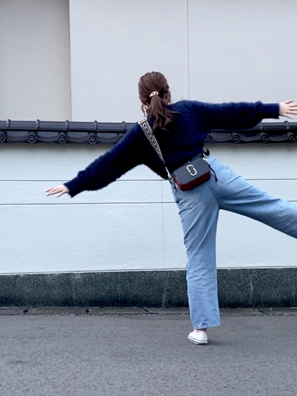 ブルー系のニット/セーター、ブルー系のデニムパンツ、ブラック系のショルダーバッグを着用したレディースの秋コーディネートの4枚目の写真