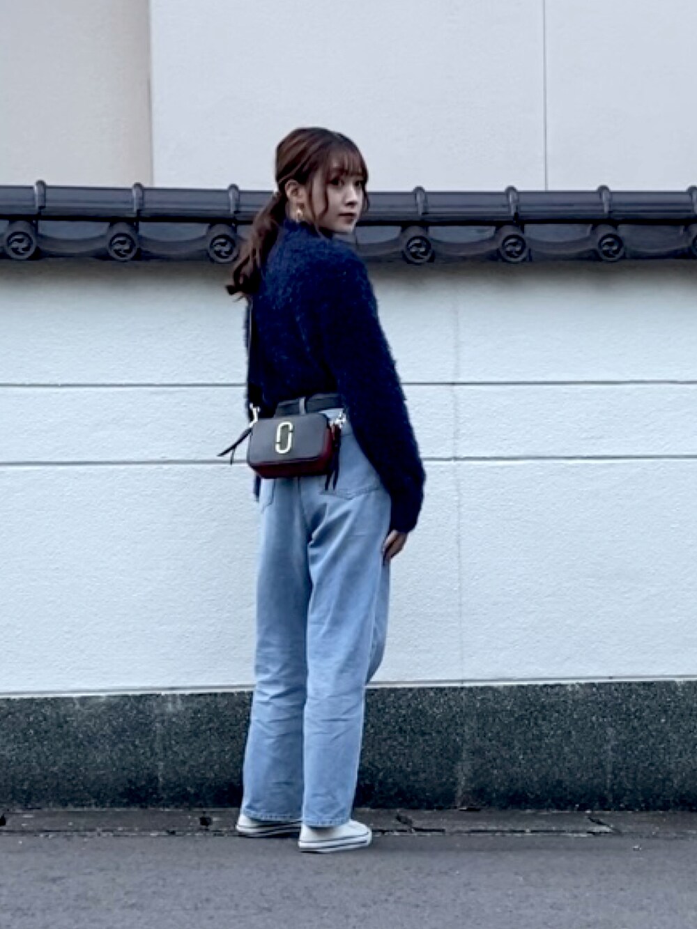 ブルー系のニット/セーター、ブルー系のデニムパンツ、ブラック系のショルダーバッグを着用したレディースの秋コーディネートの2枚目の写真