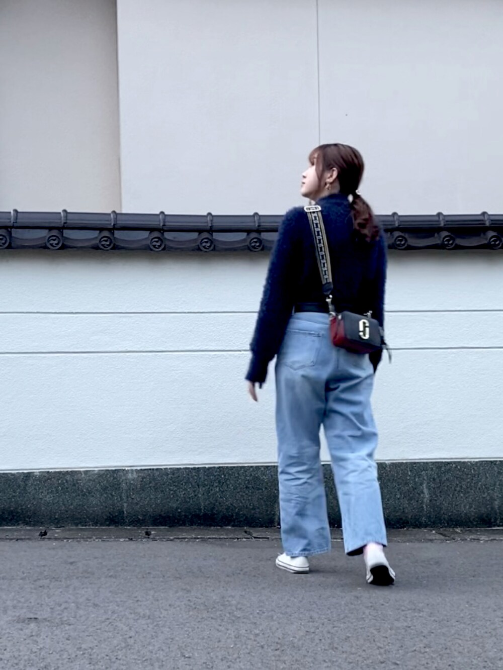 ブルー系のニット/セーター、ブルー系のデニムパンツ、ブラック系のショルダーバッグを着用したレディースの秋コーディネートの3枚目の写真