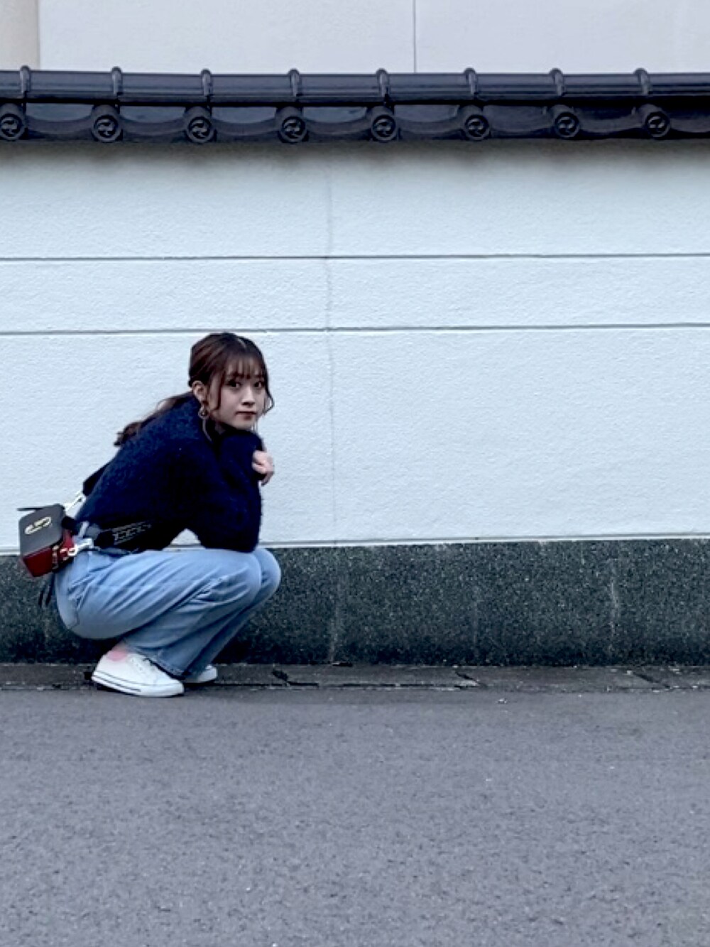 ブルー系のニット/セーター、ブルー系のデニムパンツ、ブラック系のショルダーバッグを着用したレディースの秋コーディネートの5枚目の写真