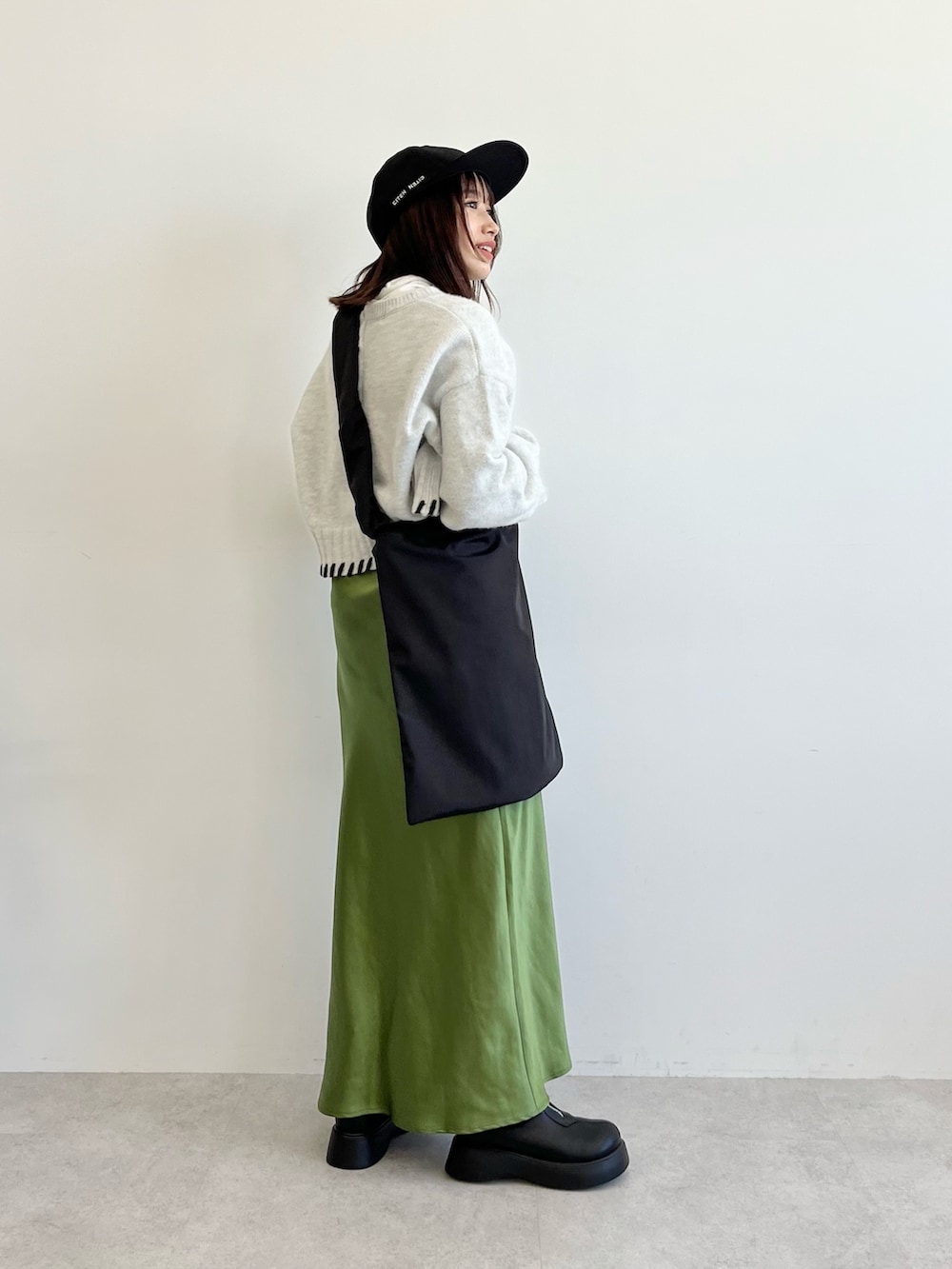 ブラック系のショルダーバッグ、グレー系のニット/セーター、グリーン系のスカートを着用したレディースの秋コーディネートの2枚目の写真