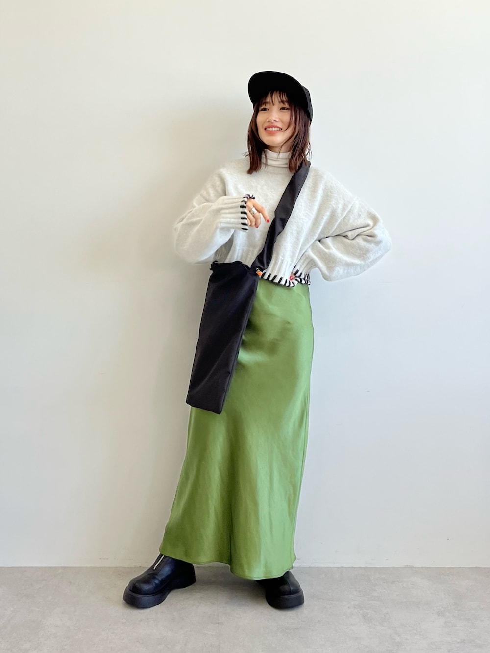 ブラック系のショルダーバッグ、グレー系のニット/セーター、グリーン系のスカートを着用したレディースの秋コーディネートの3枚目の写真