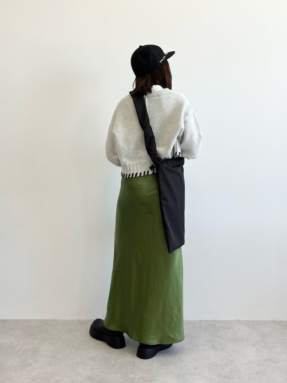 ブラック系のショルダーバッグ、グレー系のニット/セーター、グリーン系のスカートを着用したレディースの秋コーディネートの4枚目の写真