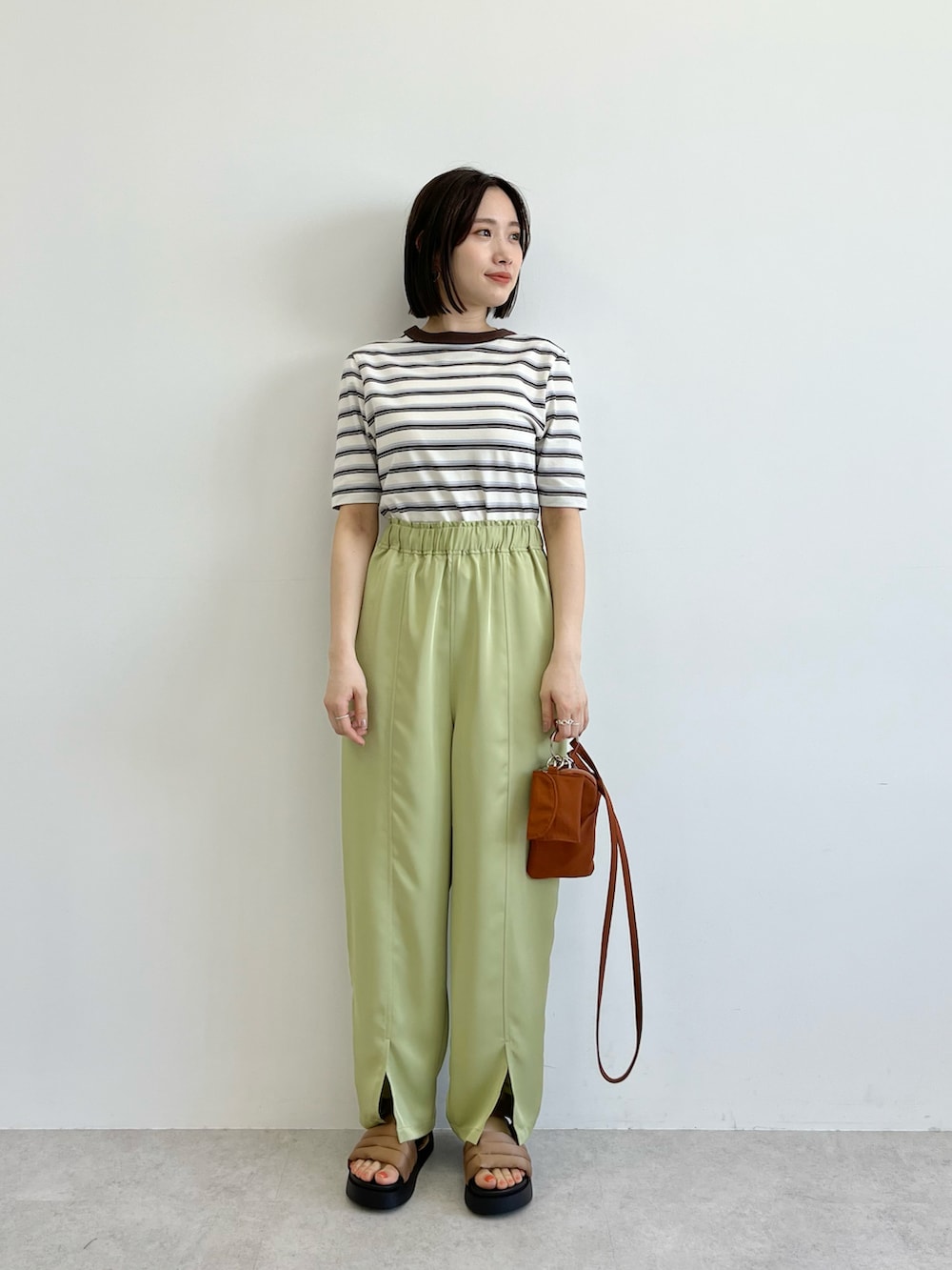 グリーン系のその他パンツ、ブラウン系のショルダーバッグ、ホワイト系のTシャツ/カットソーを着用したレディースの春コーディネートの2枚目の写真