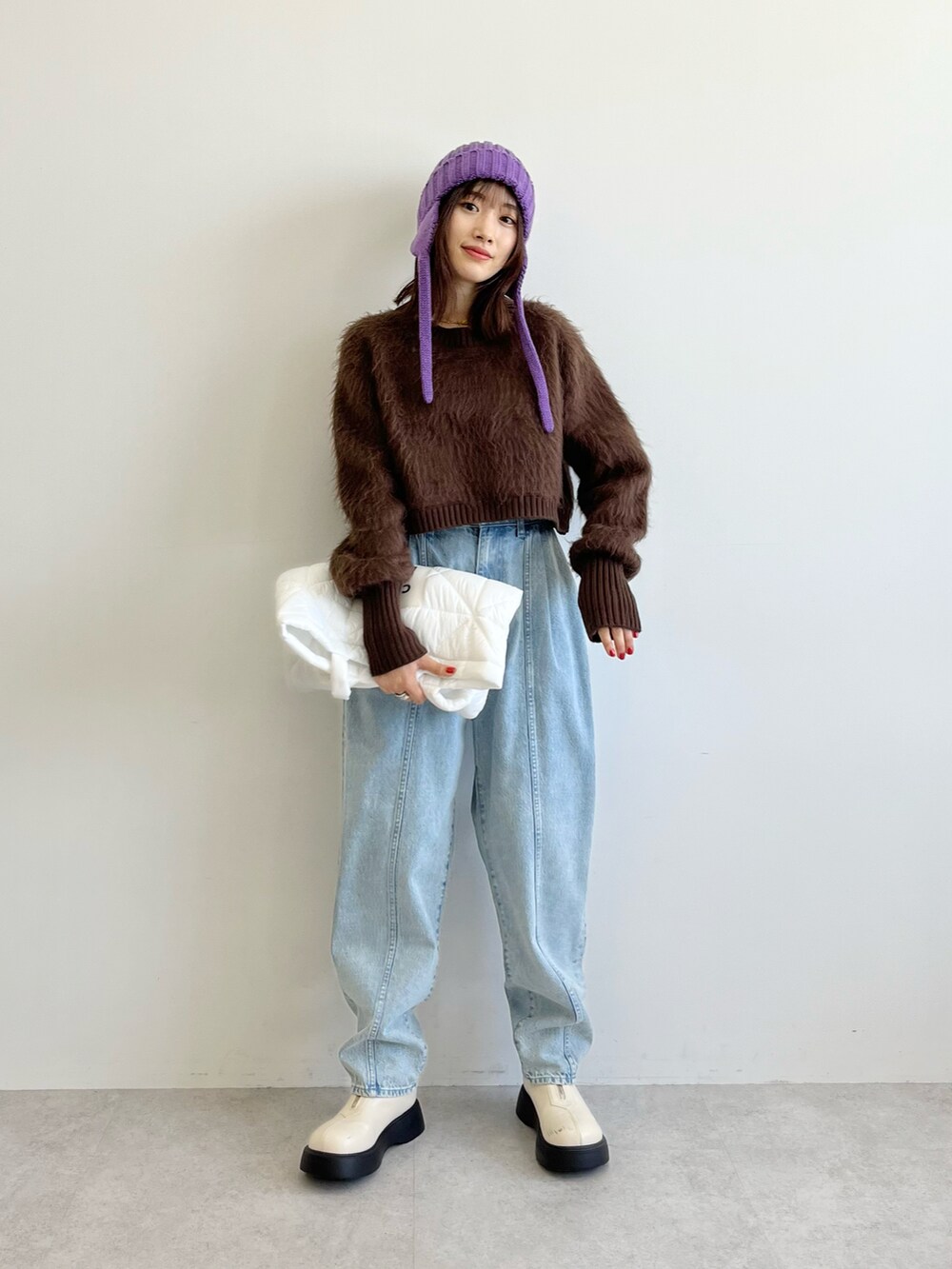 ブラウン系のニット/セーター、ホワイト系のトートバッグ、ブルー系のデニムパンツを着用したレディースの秋コーディネートの5枚目の写真