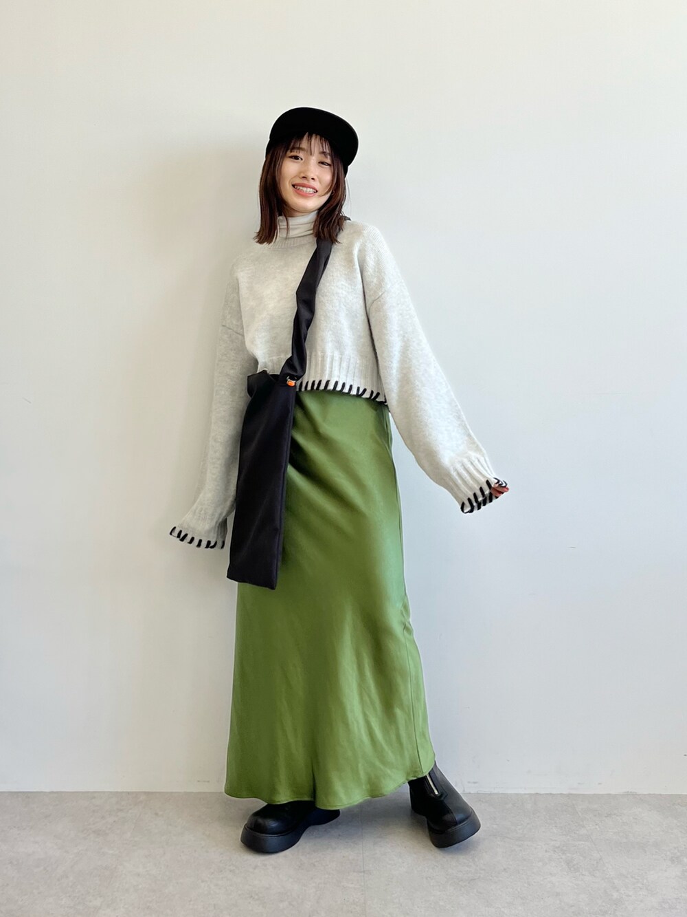 ブラック系のショルダーバッグ、グレー系のニット/セーター、グリーン系のスカートを着用したレディースの秋コーディネートの5枚目の写真