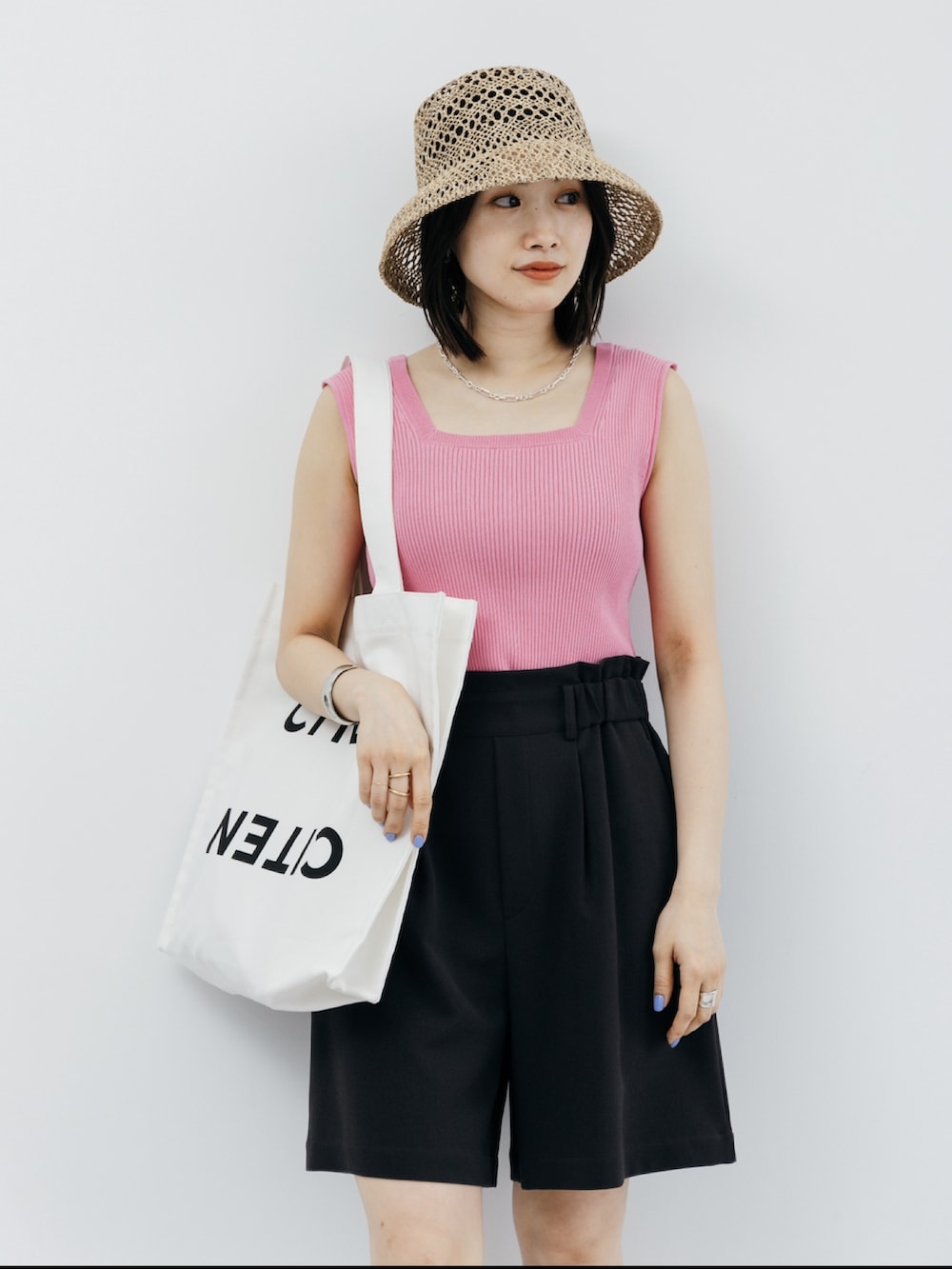 ピンク系のニット/セーター、ホワイト系のトートバッグ、ブラック系のその他パンツを着用したレディースの夏コーディネートの2枚目の写真