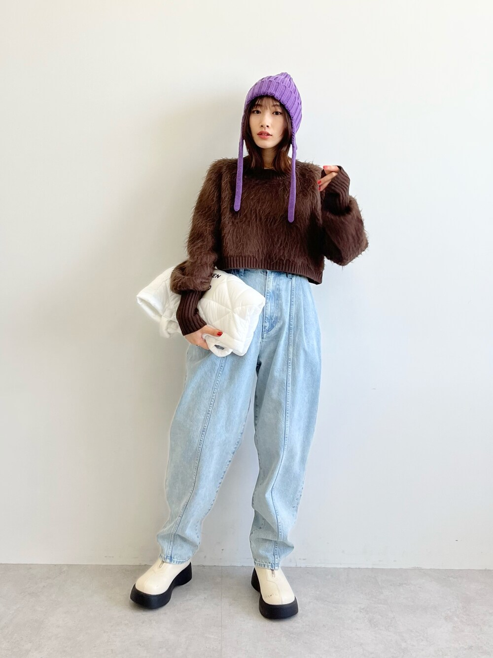 ブラウン系のニット/セーター、ホワイト系のトートバッグ、ブルー系のデニムパンツを着用したレディースの秋コーディネートの2枚目の写真