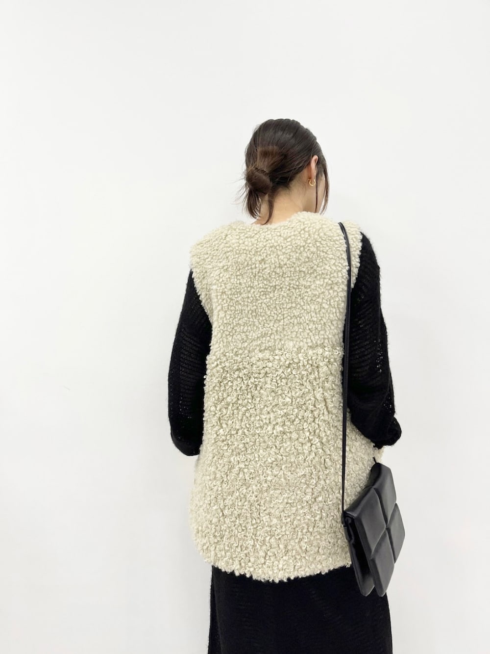 ベージュ系のベスト、ブラック系のショルダーバッグ、ブラック系のワンピースを着用したレディースの秋コーディネートの3枚目の写真