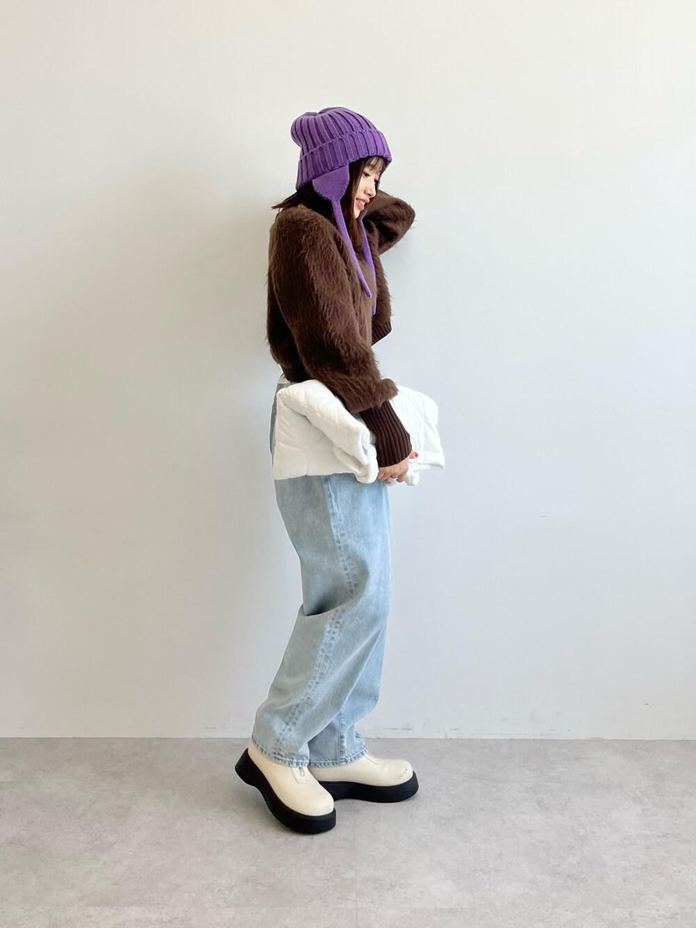 ブラウン系のニット/セーター、ホワイト系のトートバッグ、ブルー系のデニムパンツを着用したレディースの秋コーディネートの4枚目の写真