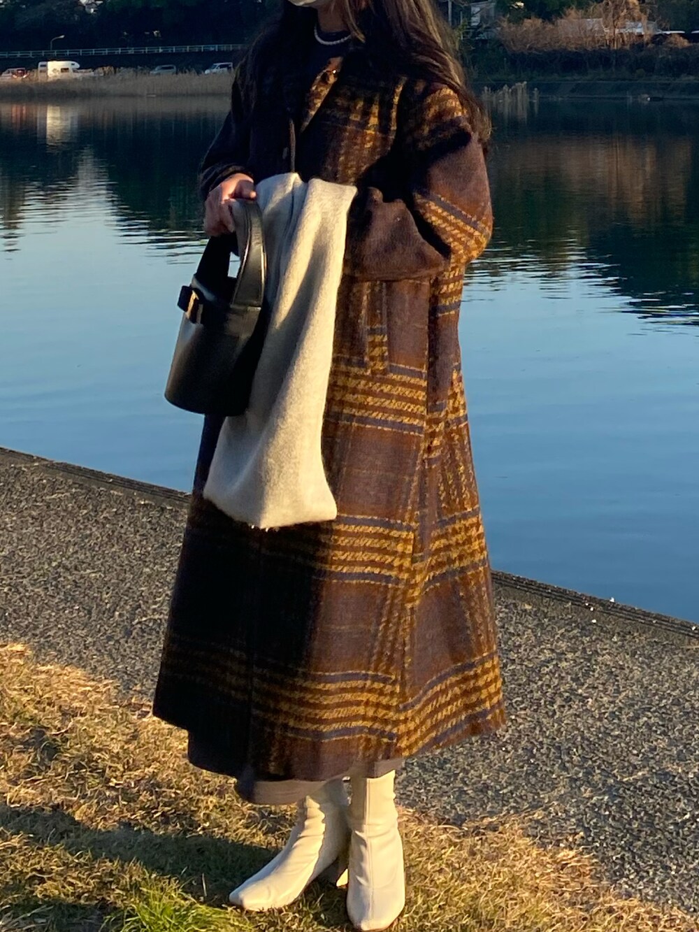 グレー系のワンピース、ホワイト系のブーツ、ブラック系のハンドバッグを着用したレディースの冬コーディネートの3枚目の写真