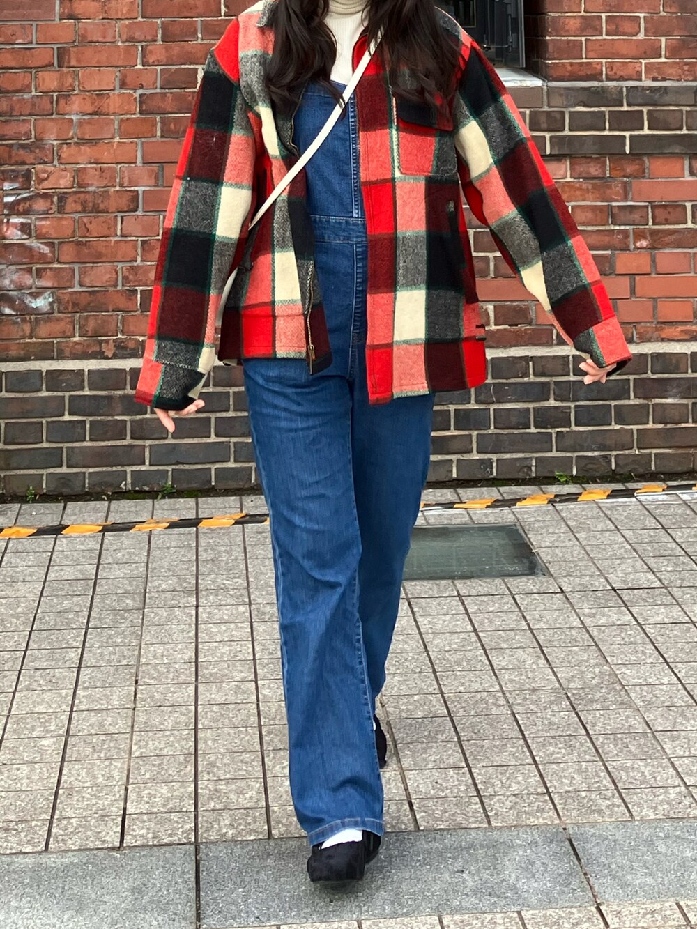 ブルー系のサロペット/オーバーオール、ブラック系のパンプス、レッド系のジャケット/アウターを着用したレディースの冬コーディネートの2枚目の写真