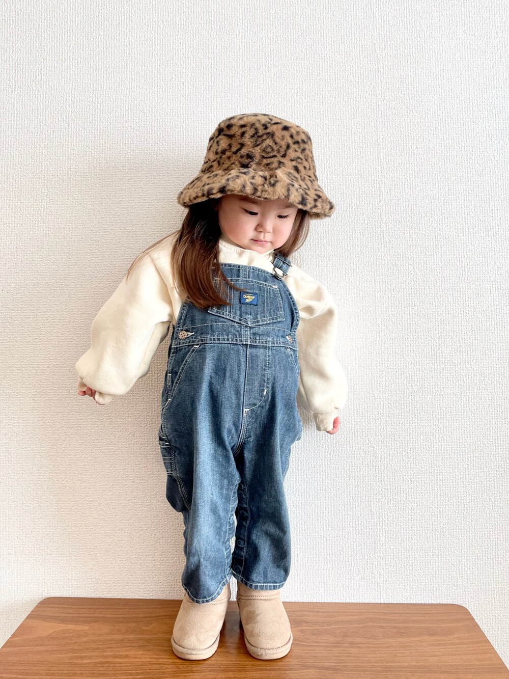 ブルー系のサロペット/オーバーオール、ベージュ系のブーツ、ベージュ系のキャップを着用したキッズの冬コーディネートの2枚目の写真