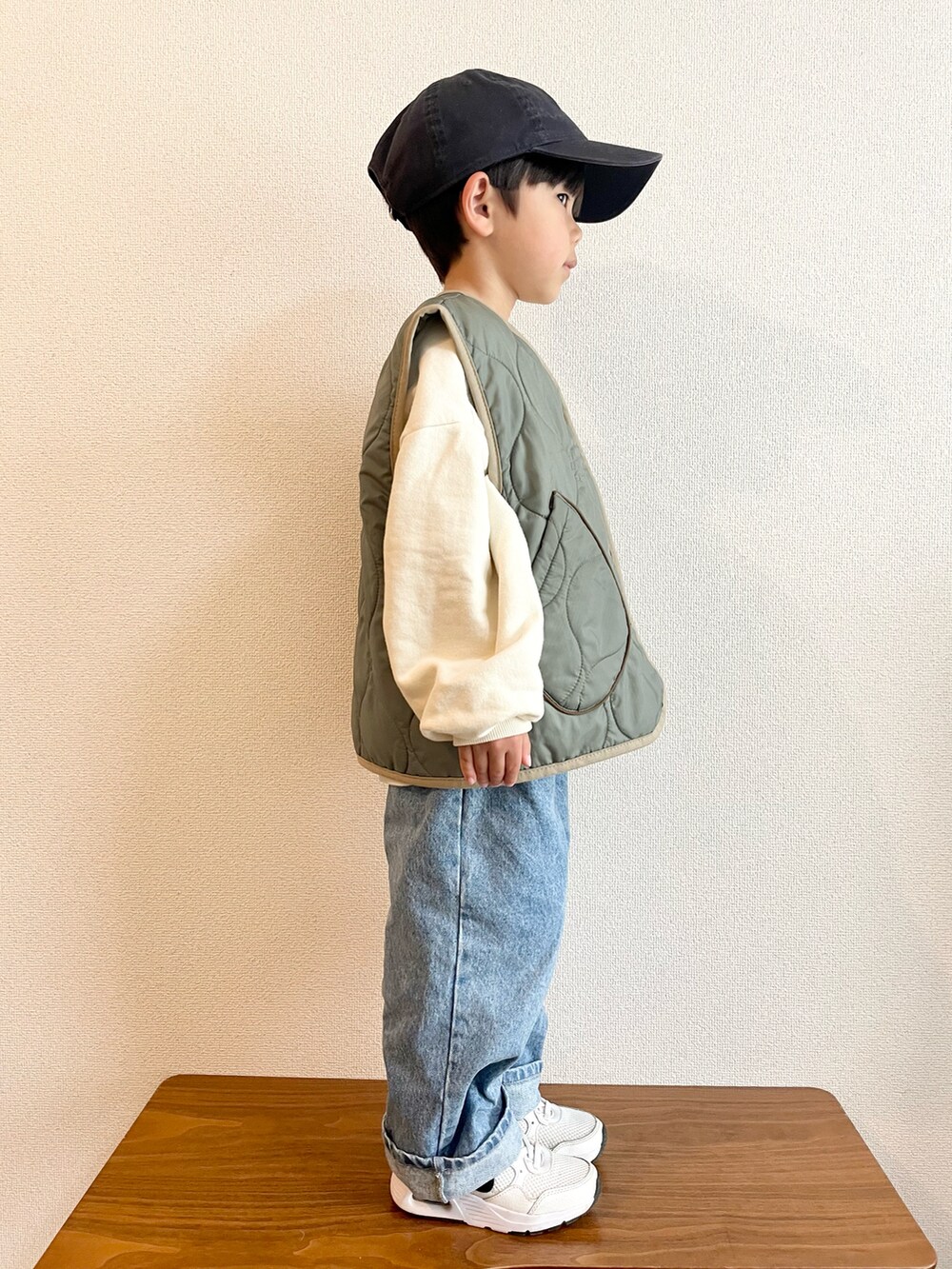 ホワイト系のスウェット、グリーン系のベスト、ブルー系のデニムパンツを着用したキッズの春コーディネートの2枚目の写真