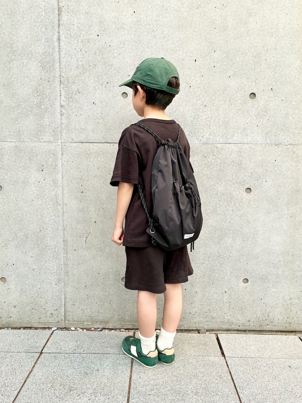 ブラック系のセットアップ、ブラック系のバックパック/リュック、グリーン系のスニーカーを着用したキッズの春コーディネートの2枚目の写真