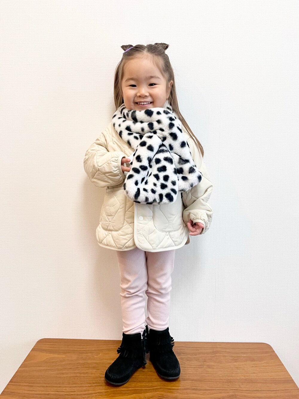 ホワイト系のジャケット/アウター、ブラック系のブーツ、ホワイト系のマフラーを着用したキッズの冬コーディネートの2枚目の写真