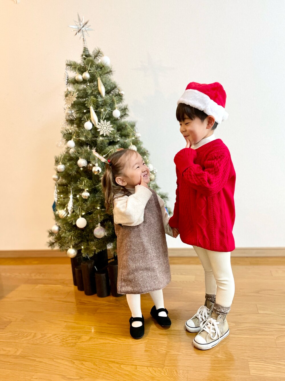 レッド系のニット/セーター、ホワイト系のニット/セーター、ブラウン系のジャンパースカートを着用したキッズの冬コーディネートの2枚目の写真