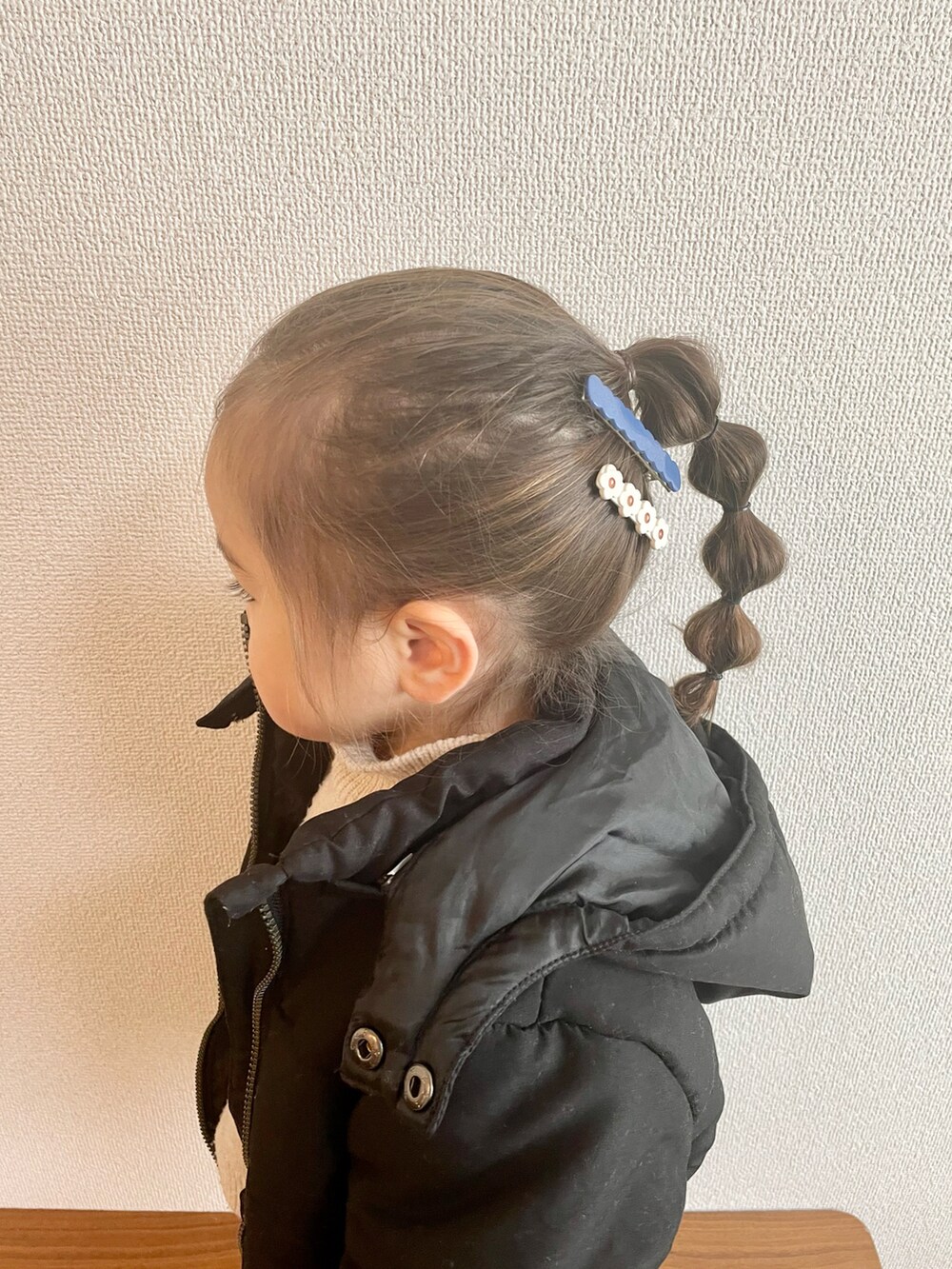 ブラック系のダウンジャケット/コート、ホワイト系のニット/セーター、ブラック系のバレエシューズを着用したキッズの冬コーディネートの2枚目の写真