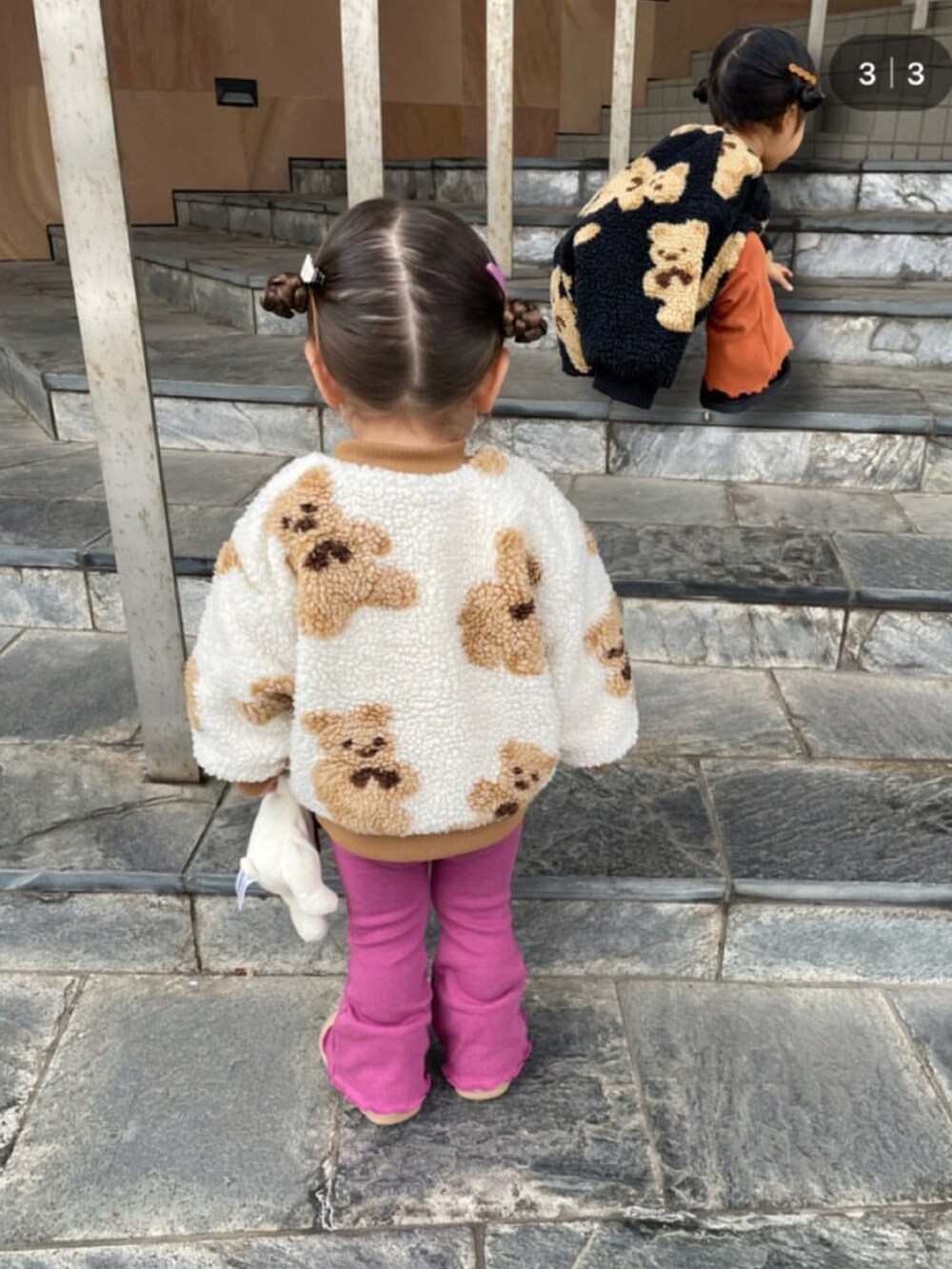 レッド系のニット/セーター、ホワイト系のニット/セーター、ブラウン系のジャンパースカートを着用したキッズの冬コーディネートの4枚目の写真