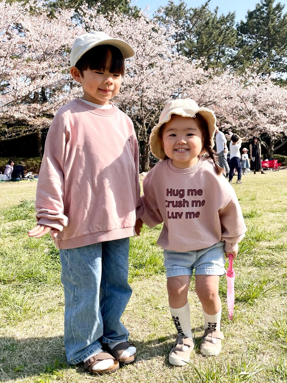 ピンク系のスウェット、ブルー系のデニムパンツ、ブラウン系のサンダルを着用したキッズの春コーディネートの3枚目の写真