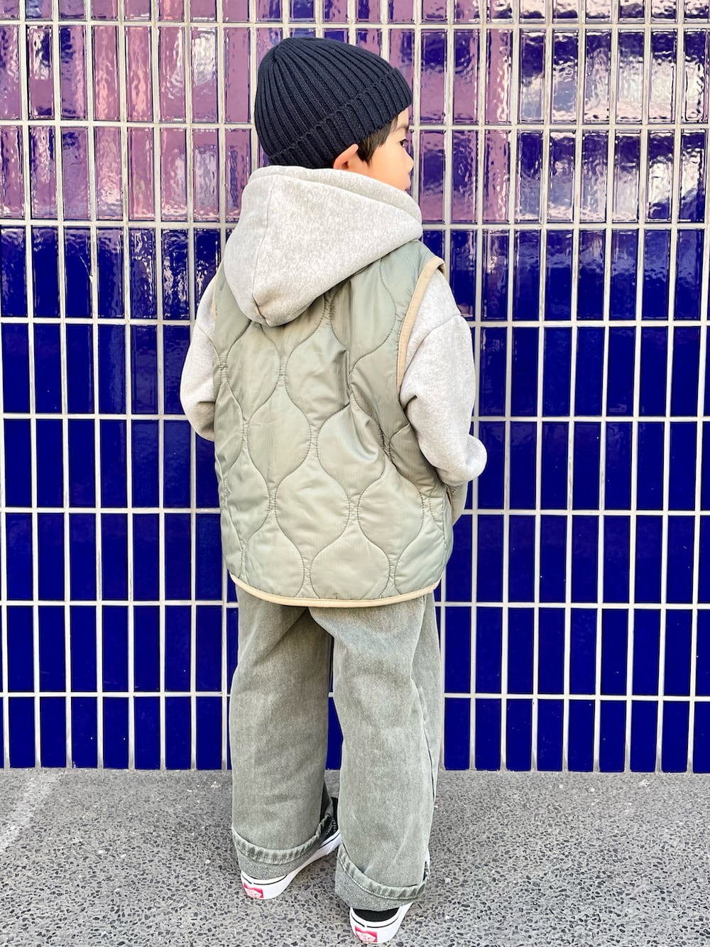 グレー系のパーカー、グリーン系のベスト、グリーン系のデニムパンツを着用したキッズの冬コーディネートの4枚目の写真
