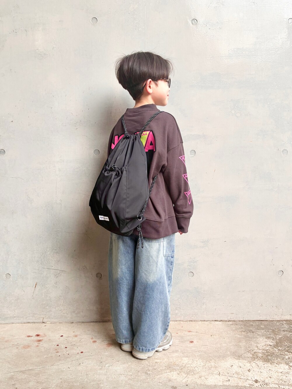 ブラウン系のスウェット、ブルー系のデニムパンツ、ブラック系のバックパック/リュックを着用したキッズの春コーディネートの2枚目の写真