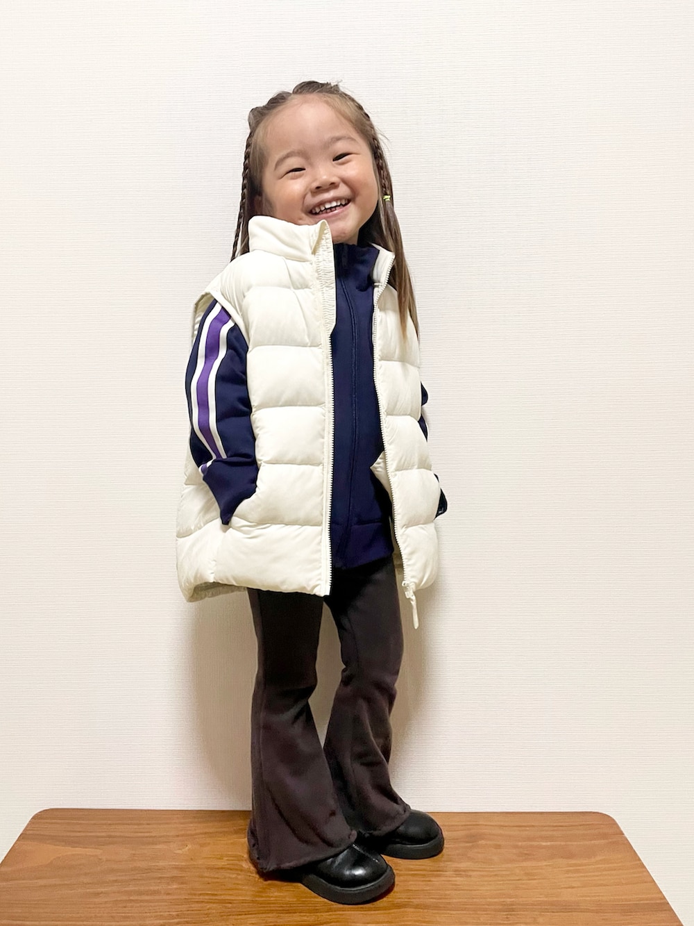 ホワイト系のダウンベスト、ブルー系のジャージ、グレー系のその他パンツを着用したキッズの冬コーディネートの2枚目の写真