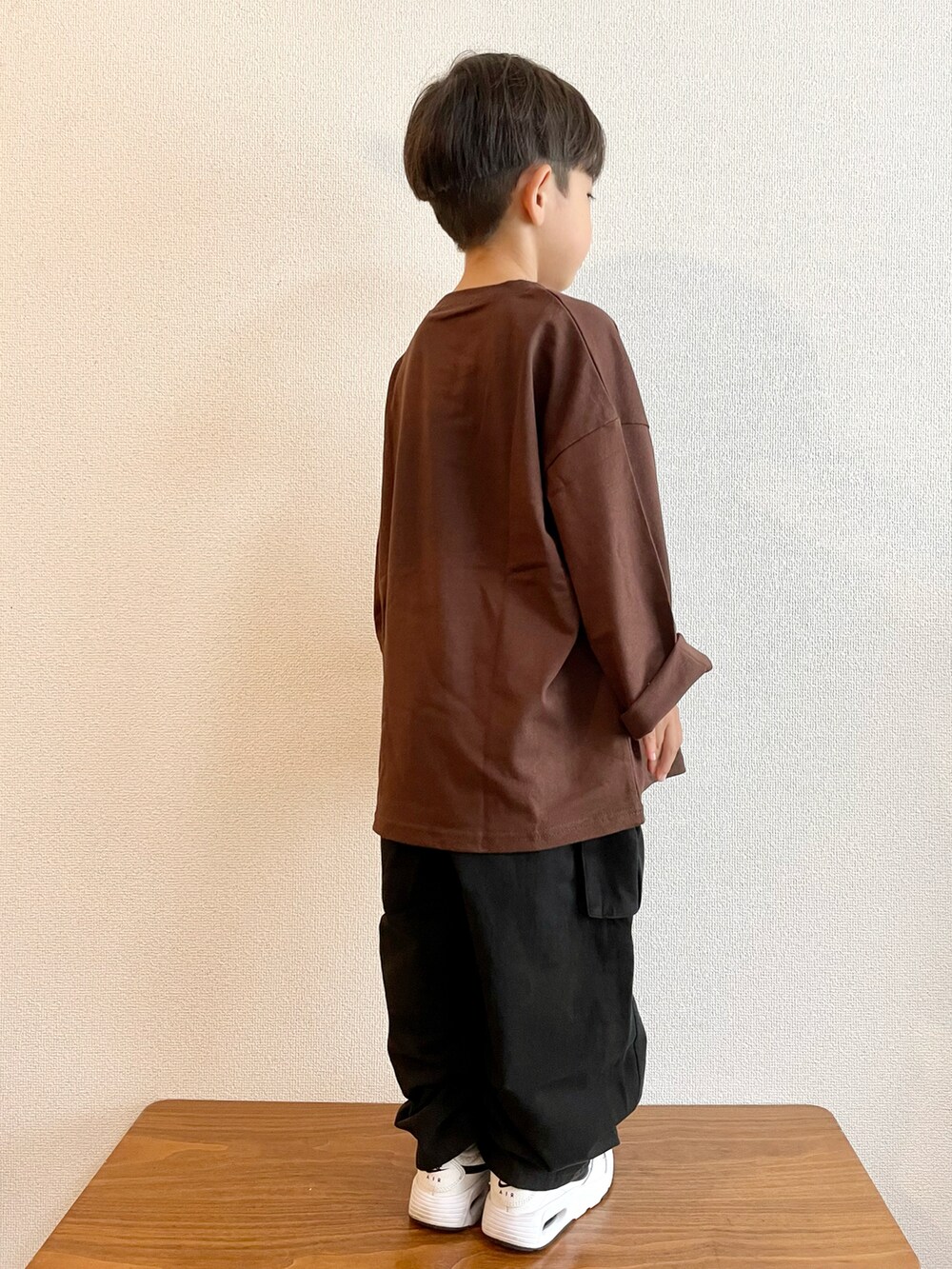 ブラウン系のTシャツ/カットソー、ブラック系のカーゴパンツ、ホワイト系のスニーカーを着用したキッズの秋コーディネートの2枚目の写真