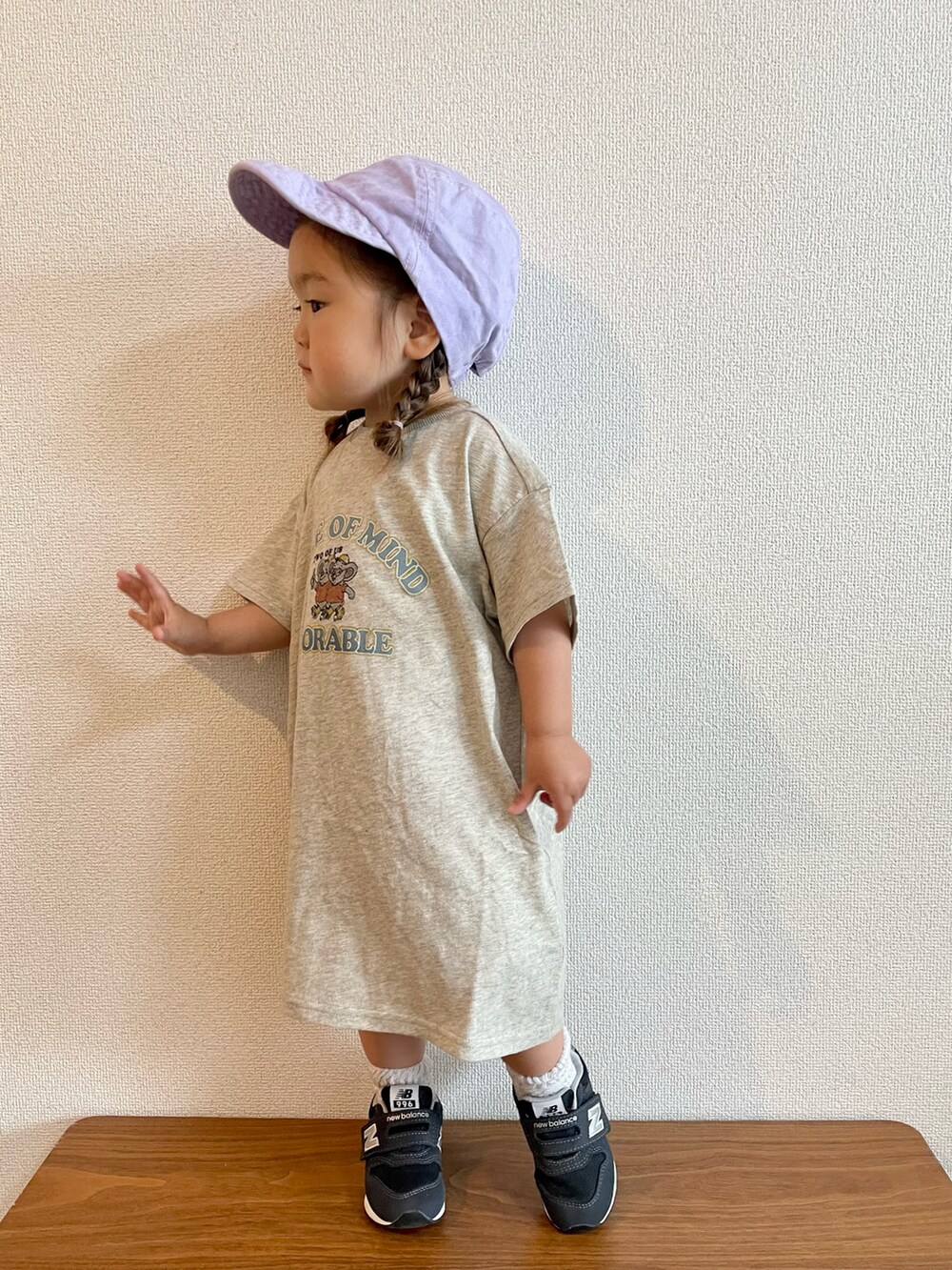 ホワイト系のワンピース、ブルー系のスニーカー、パープル系のキャップを着用したキッズの春コーディネートの2枚目の写真