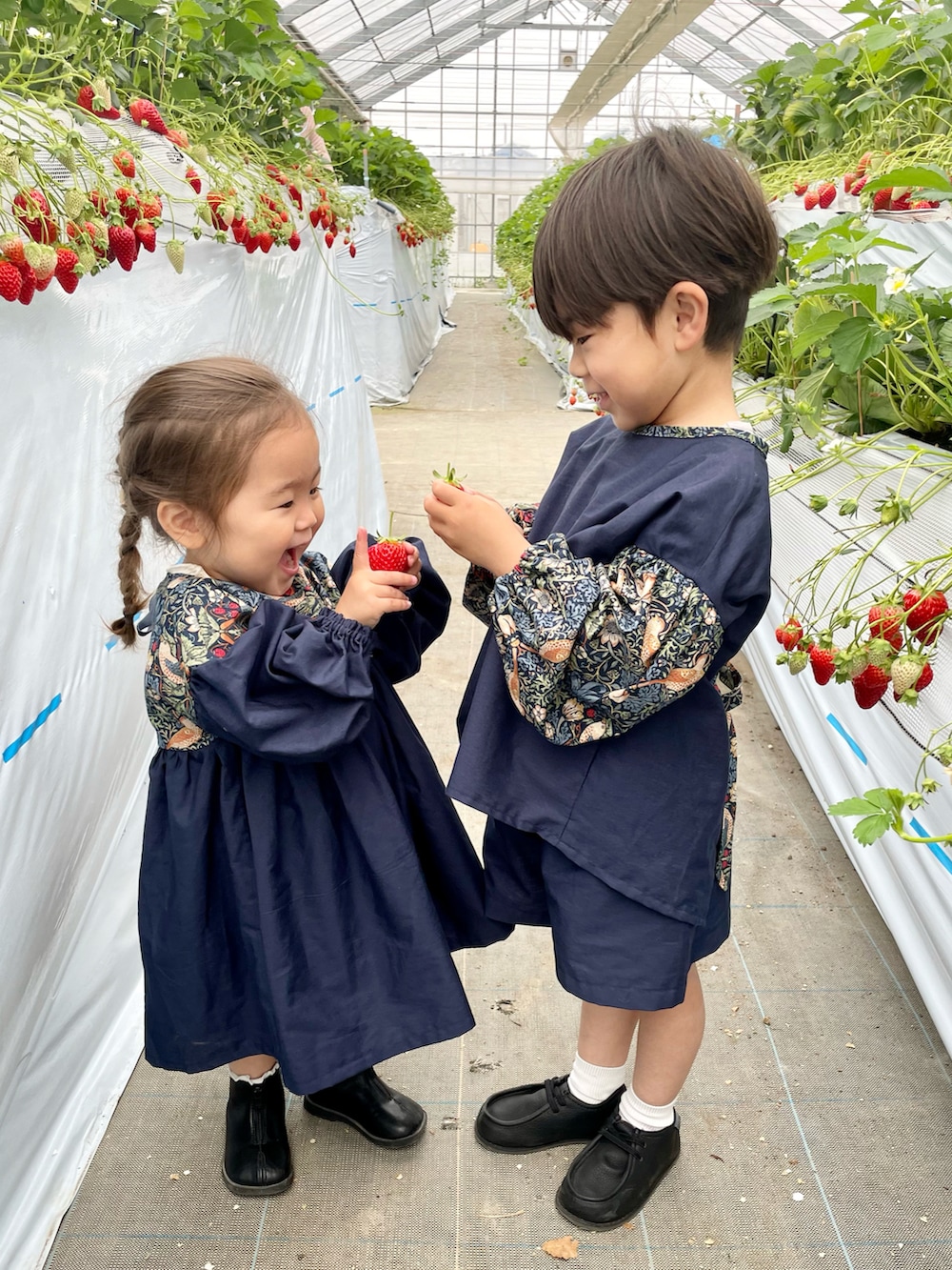 ブルー系のワンピース、ブラック系のブーツ、ブルー系のシャツ/ブラウスを着用したキッズの春コーディネートの3枚目の写真