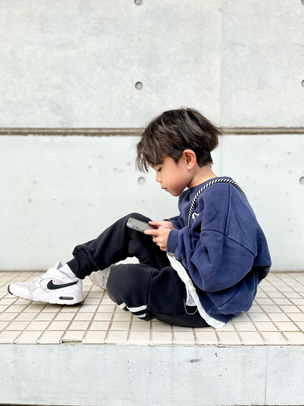 ブルー系のスウェット、ブラック系のスウェットパンツ、ホワイト系のスニーカーを着用したキッズの冬コーディネートの2枚目の写真