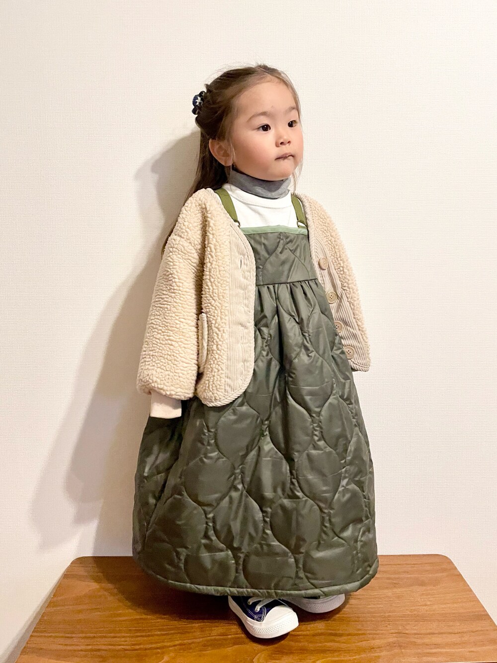 ホワイト系のTシャツ/カットソー、グリーン系のジャンパースカート、パープル系のスニーカーを着用したキッズの冬コーディネートの2枚目の写真