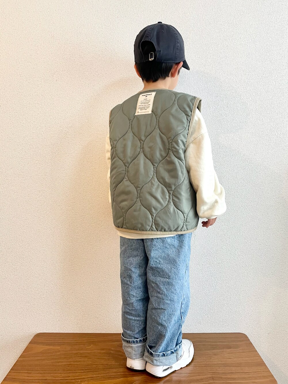 ホワイト系のスウェット、グリーン系のベスト、ブルー系のデニムパンツを着用したキッズの春コーディネートの3枚目の写真