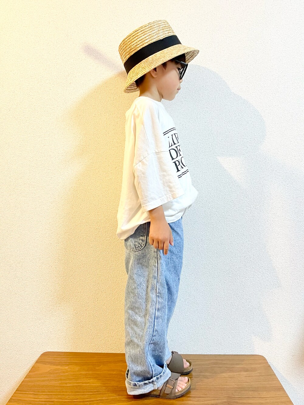 ホワイト系のTシャツ/カットソー、ブルー系のデニムパンツ、ブラウン系のサンダルを着用したキッズの夏コーディネートの2枚目の写真