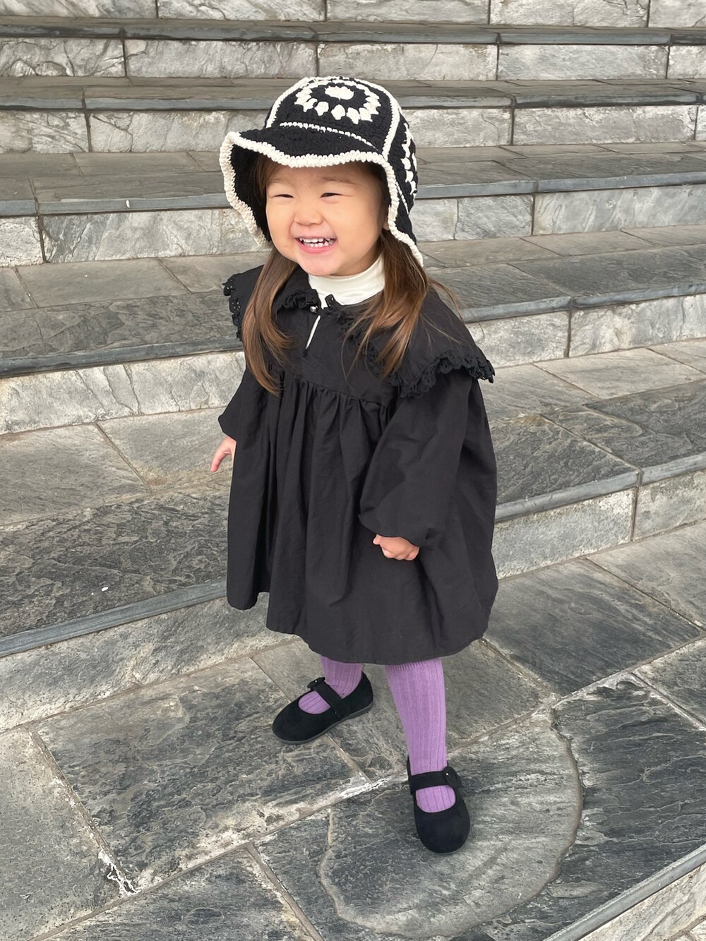 ベージュ系のTシャツ/カットソー、ブラック系のワンピース、ブラック系のバレエシューズを着用したキッズの冬コーディネートの2枚目の写真