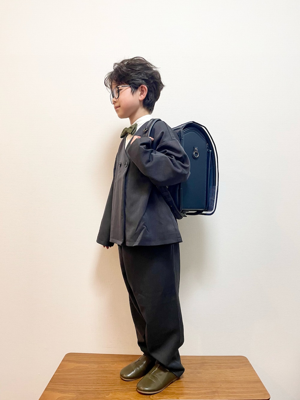 グレー系のスーツセット、グリーン系のスリッポン、ブルー系のランドセルを着用したキッズの春コーディネートの2枚目の写真