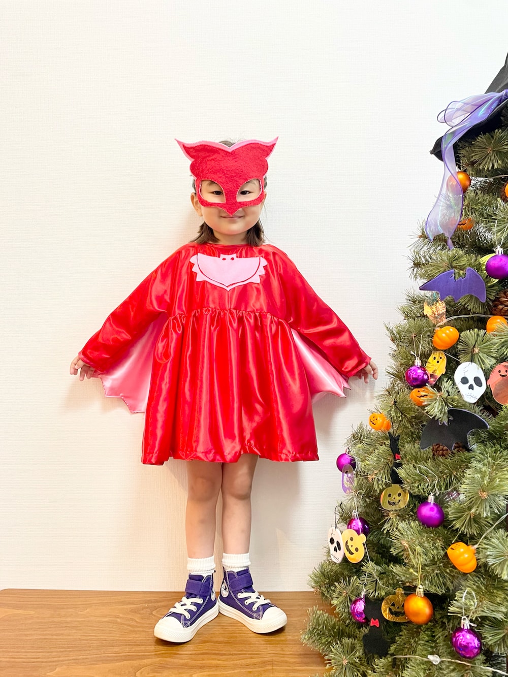 パープル系のスニーカー、レッド系のワンピースを着用したキッズの秋コーディネートの2枚目の写真