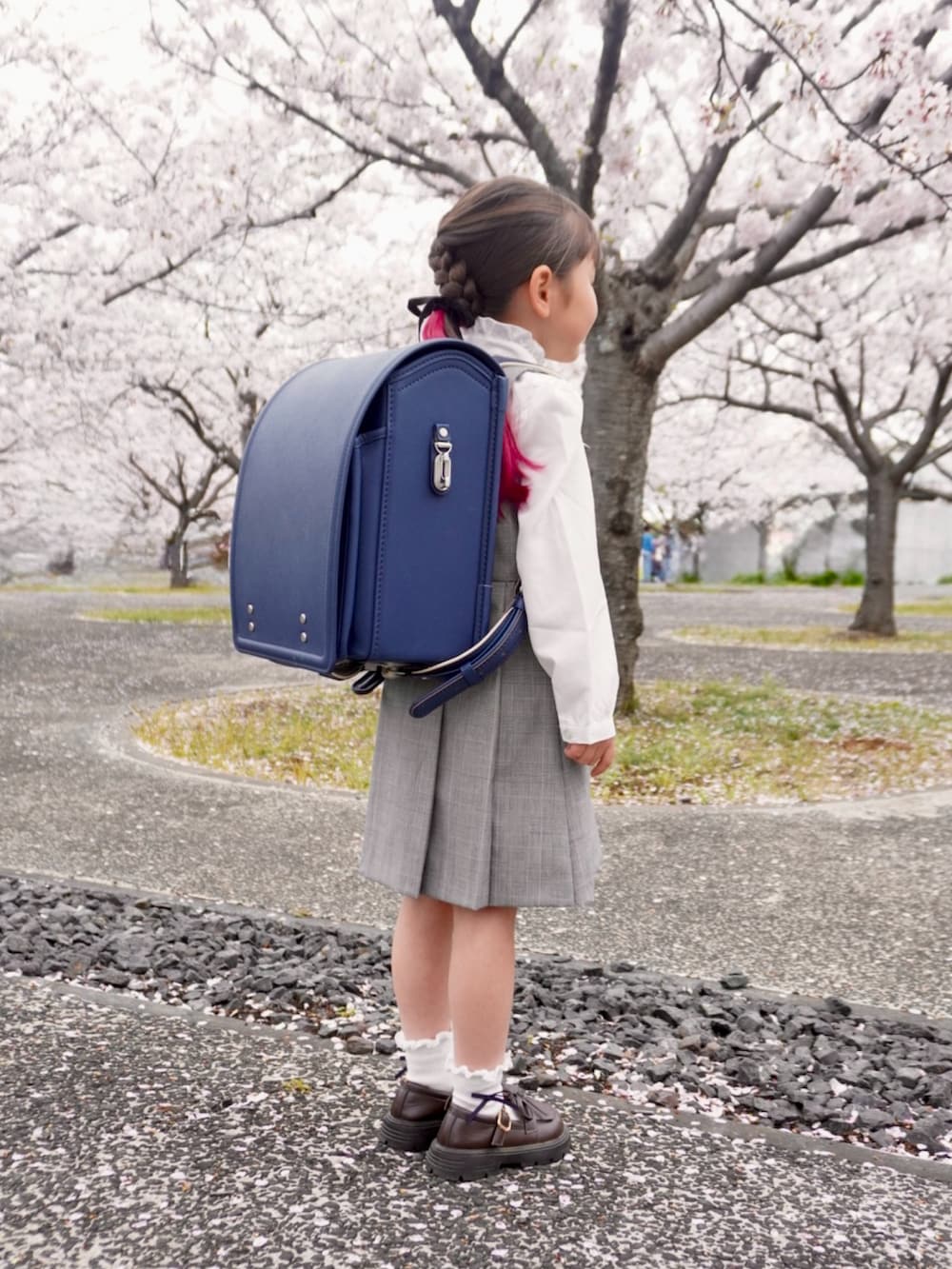 ホワイト系のシャツ/ブラウス、グレー系のジャンパースカート、ブルー系のランドセルを着用したキッズの春コーディネートの2枚目の写真