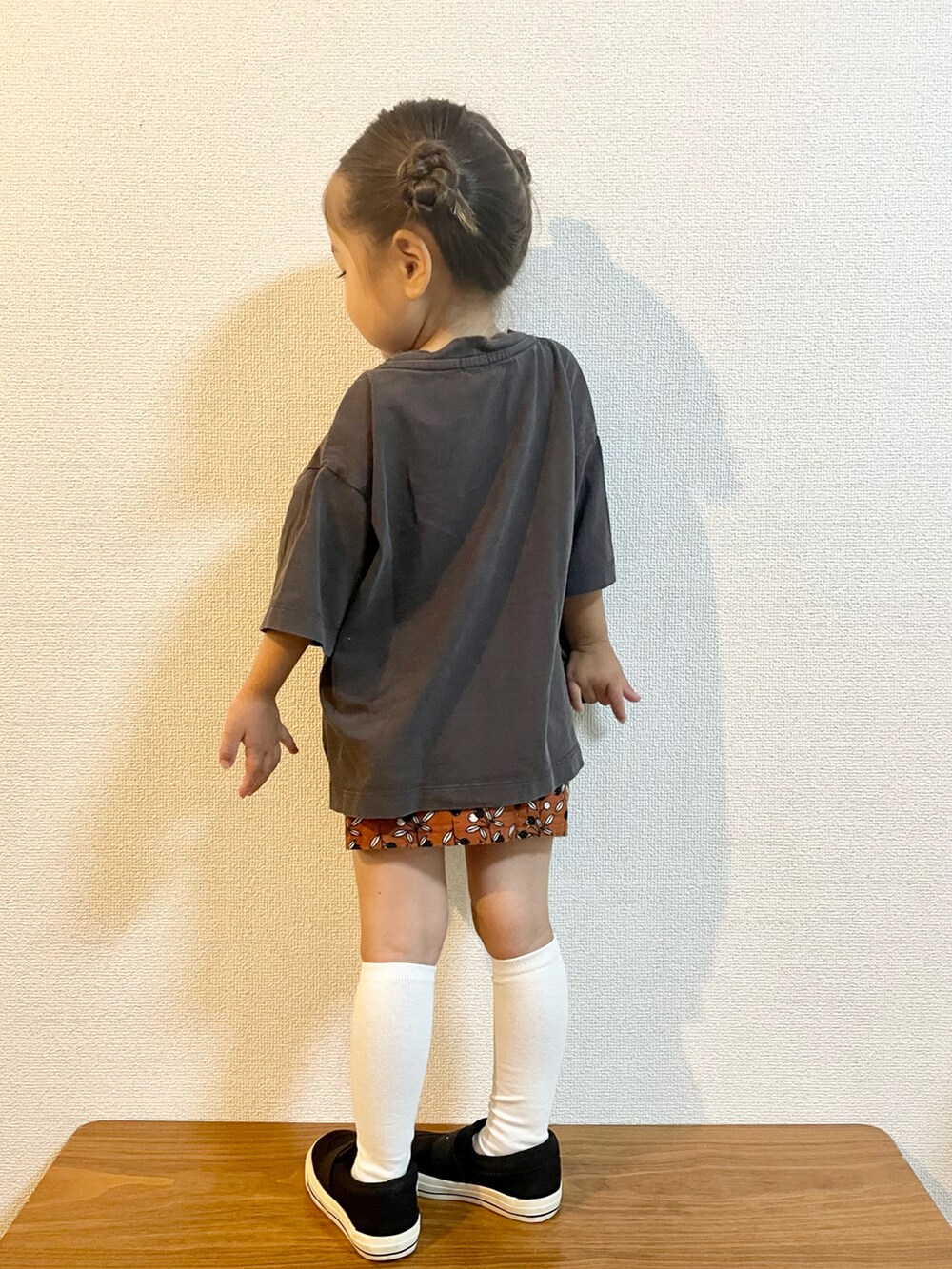 グレー系のTシャツ/カットソー、オレンジ系のスカート、ブラック系のスニーカーを着用したキッズの秋コーディネートの3枚目の写真