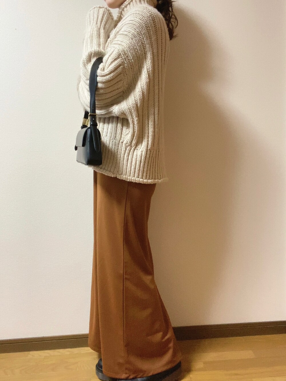 ブラック系のダウンジャケット/コート、ブラック系のショルダーバッグ、ブラウン系のワンピースを着用したレディースの冬コーディネートの2枚目の写真